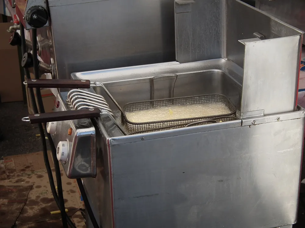 Friteuse en inox avec panier plongé dans une huile en ébullition
